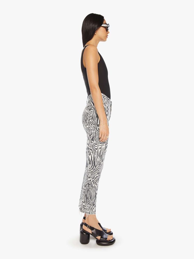 Side view of a woman high-rise straight leg with an ankle-length inseam and a frayed hem in a black and white graphic zebra print.