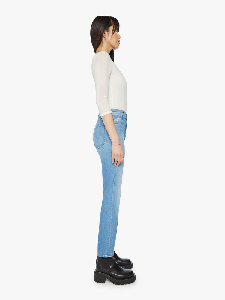 Side  view of a woman high rise jean with a straight leg, button fly and a 28.25-inch inseam with a clean hem in light blue wash.
