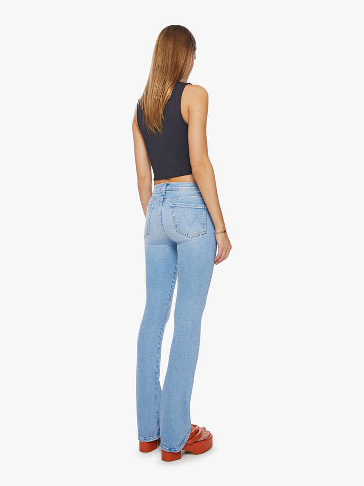 Back view of a woman mid-rise jeans with a narrow straight leg and a long 34-inch inseam with a clean hem in a light blue with distressed details and a tear knee.