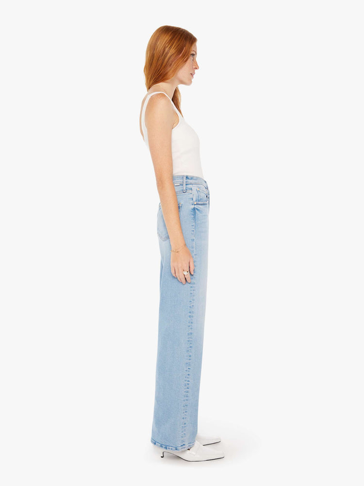 Side view of a woman super high-waisted jeans with a loose fit, wide leg and 32-inch inseam with a clean hem in a light blue wash.