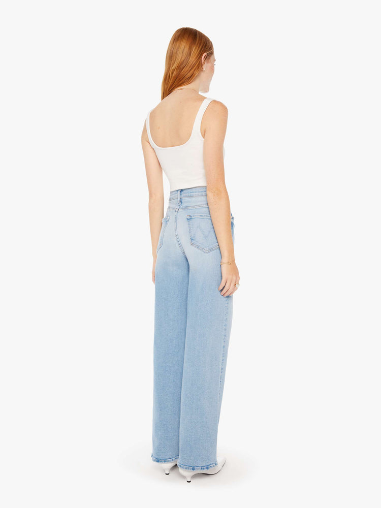 Back view of a woman super high-waisted jeans with a loose fit, wide leg and 32-inch inseam with a clean hem in a light blue wash.