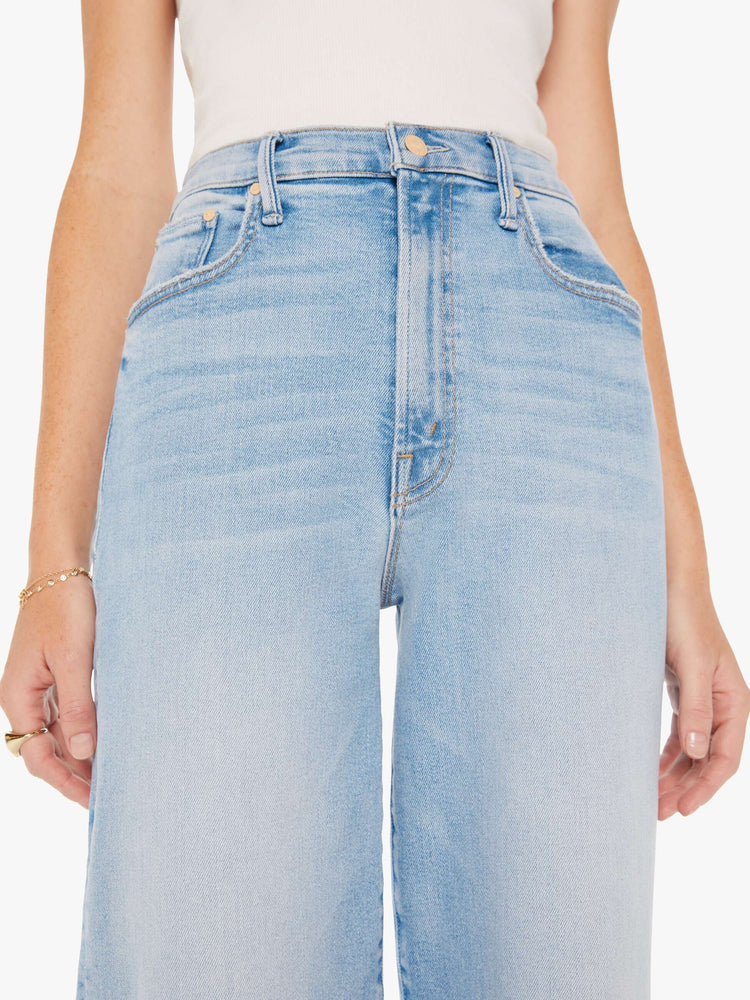 Close up view of a woman super high-waisted jeans with a loose fit, wide leg and 32-inch inseam with a clean hem in a light blue wash.