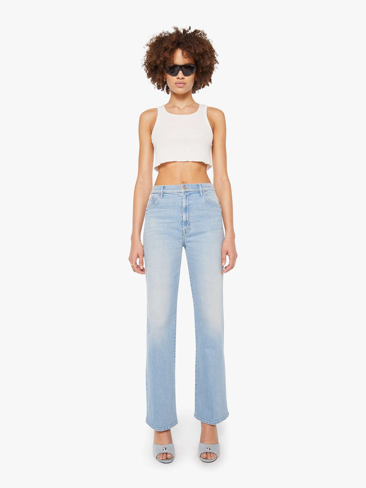 Front view of a woman in light blue super high-rise jeans with a loose fit, wide leg, zip fly and 32-inch inseam with a clean hem. 