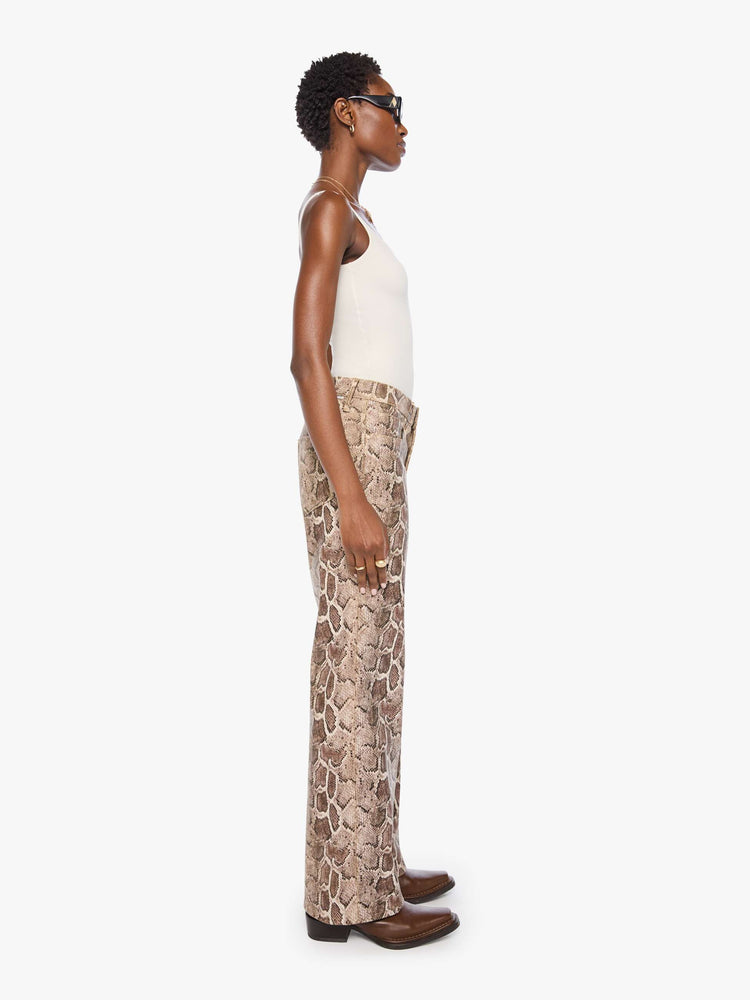 Side view of a woman in a snake skin super high-rise pants with a loose fit, wide leg, zip fly and 32-inch inseam with a clean hem.
