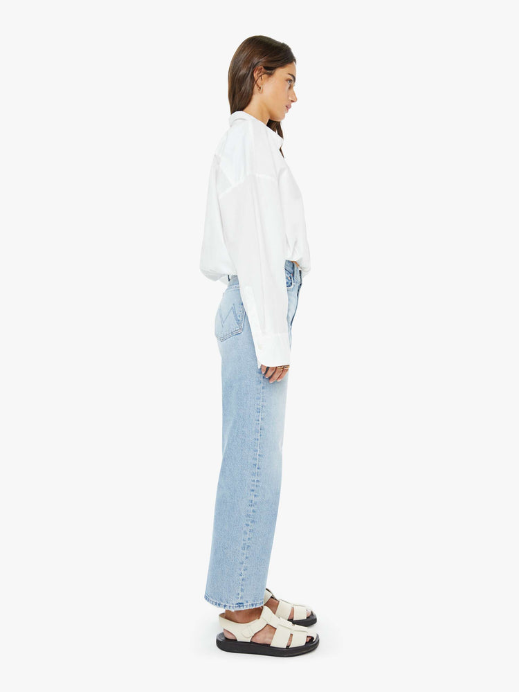 Side view of a woman in a light blue high-rise jeans with a wide straight leg, zip fly and 28.25-inch inseam with a clean hem.