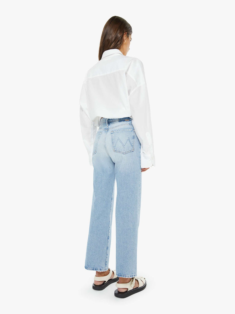 Side view of a woman in a light blue high-rise jeans with a wide straight leg, zip fly and 28.25-inch inseam with a clean hem.
