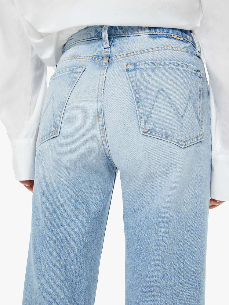 Close up view of a woman in a light blue high-rise jeans with a wide straight leg, zip fly and 28.25-inch inseam with a clean hem.
