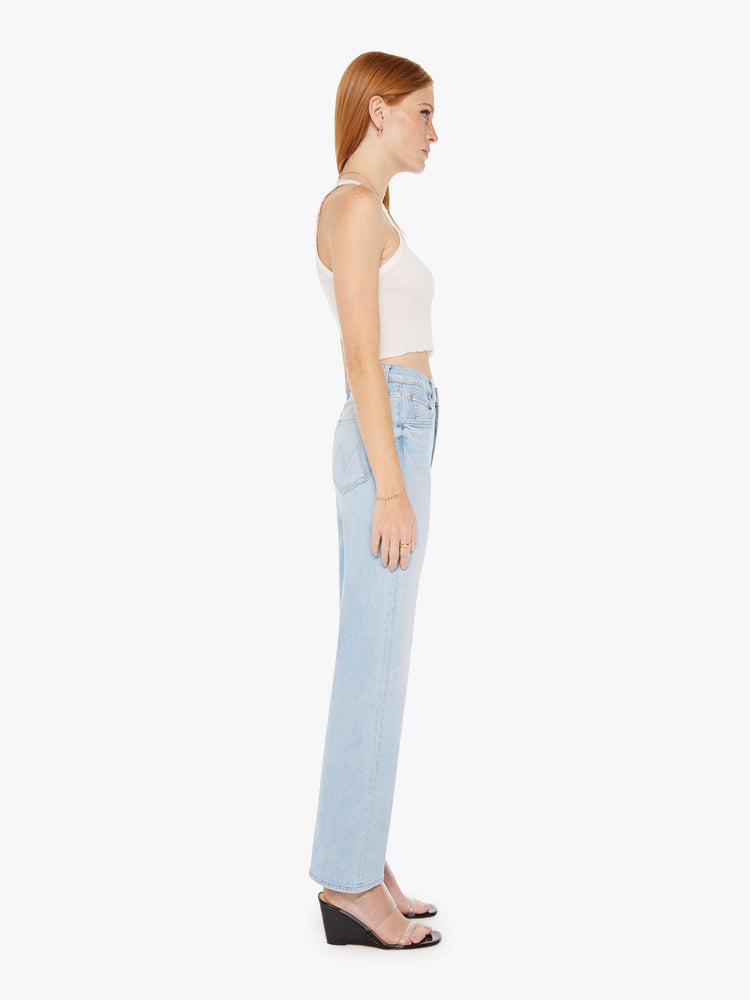 Side view of a womens light blue wash jean featuring a high rise and a wide straight leg with a clean flood length hem.