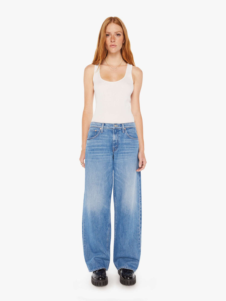 Front view of woman in a mid blue low-rise jeans with a loose wide leg and a long 32-inch inseam with a clean hem.
