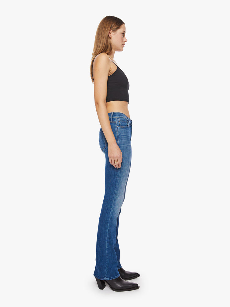 Side view of a woman mid-rise bootcut has a 34-inch inseam and a clean hem in a mid-blue wash.