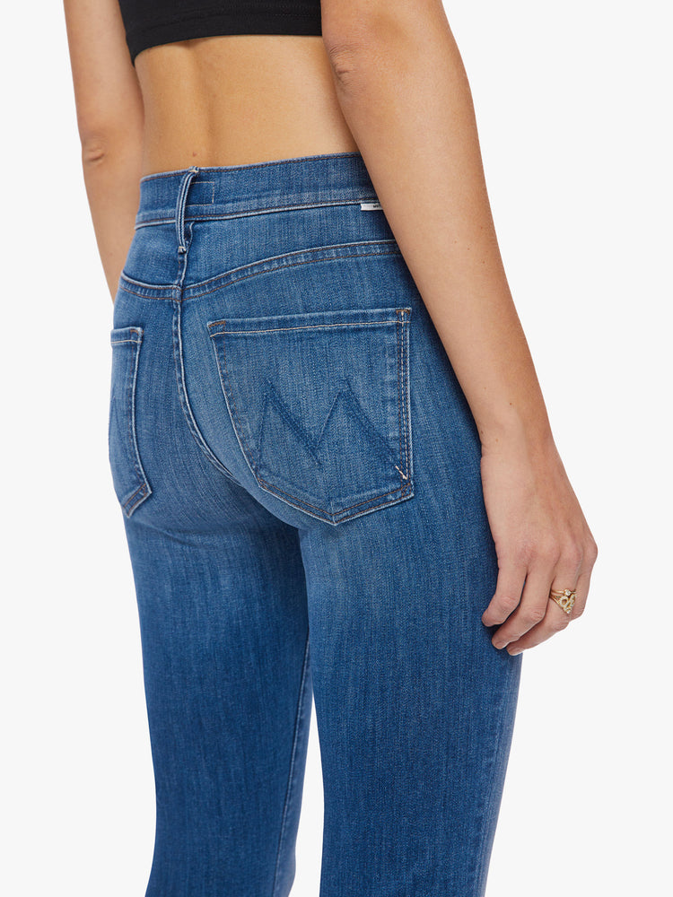 Back close up view of a woman mid-rise bootcut has a 34-inch inseam and a clean hem in a mid-blue wash.