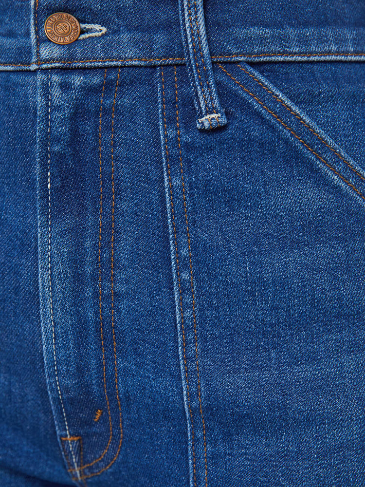 Detailed view view of a woman in dark blue super high-waisted jeans with a loose wide leg, utility-inspired patch pockets, and subltle whiskering and fading at the knee. 