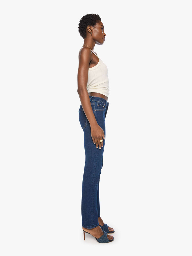 Side view of a woman in a dark blue mid-rise straight leg with a zip fly, 31-inch inseam and a clean hem.