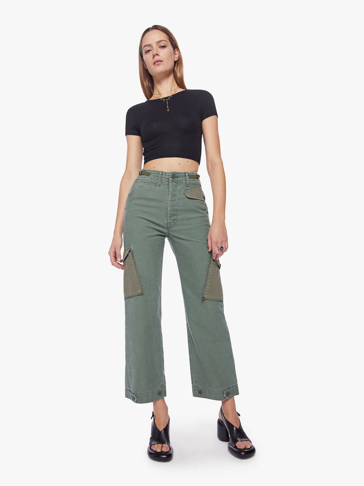 Front view of a woman army-green hue cargo pants with a super high rise, patch pockets, a 30-inch inseam and buttons on the hem.