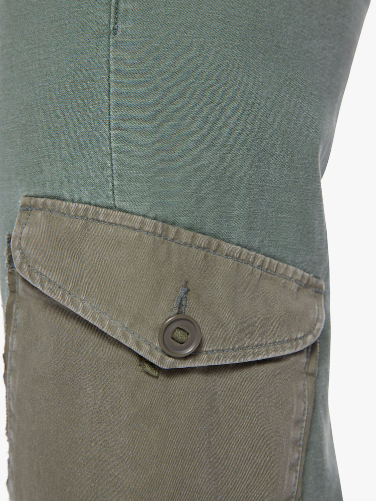 Pocket close up view view of a woman army-green hue cargo pants with a super high rise, patch pockets, a 30-inch inseam and buttons on the hem.