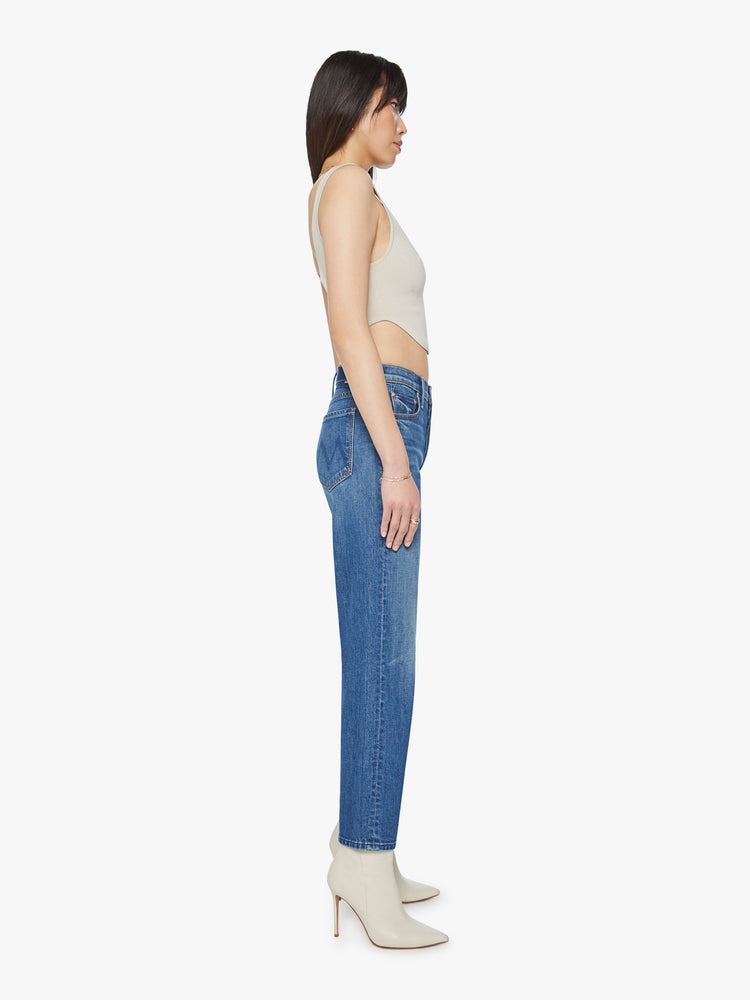 Side view of a woman classic blue jeans with a high rise, button fly, straight leg and a 31-inch inseam with a clean hem.