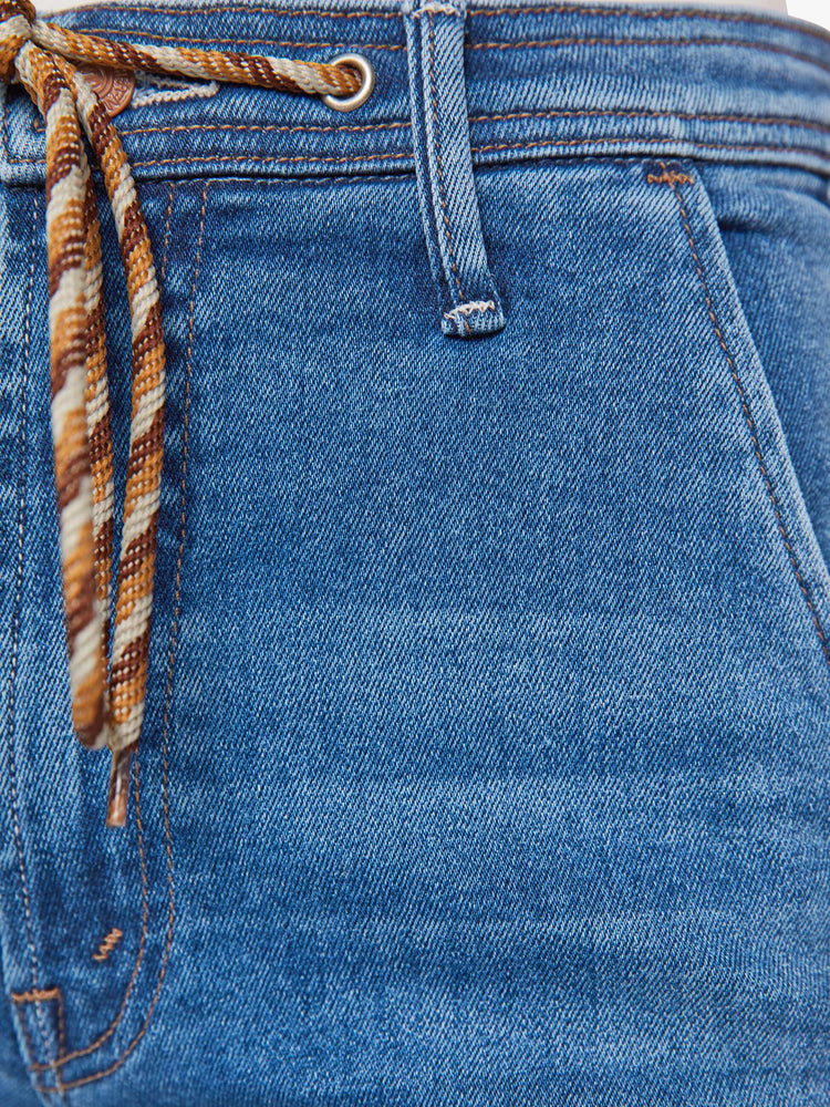 Swatch view of a woman in a mid-blue wide leg jeans with a high rise, zip fly, colorful drawstring waistband and a long 32-inch inseam with a clean hem.