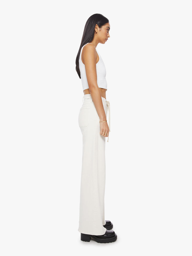 Side view of a woman wide-leg pant with a high rise, drawstring waistband and a 32-inch inseam with a clean hem in an off-white hue.