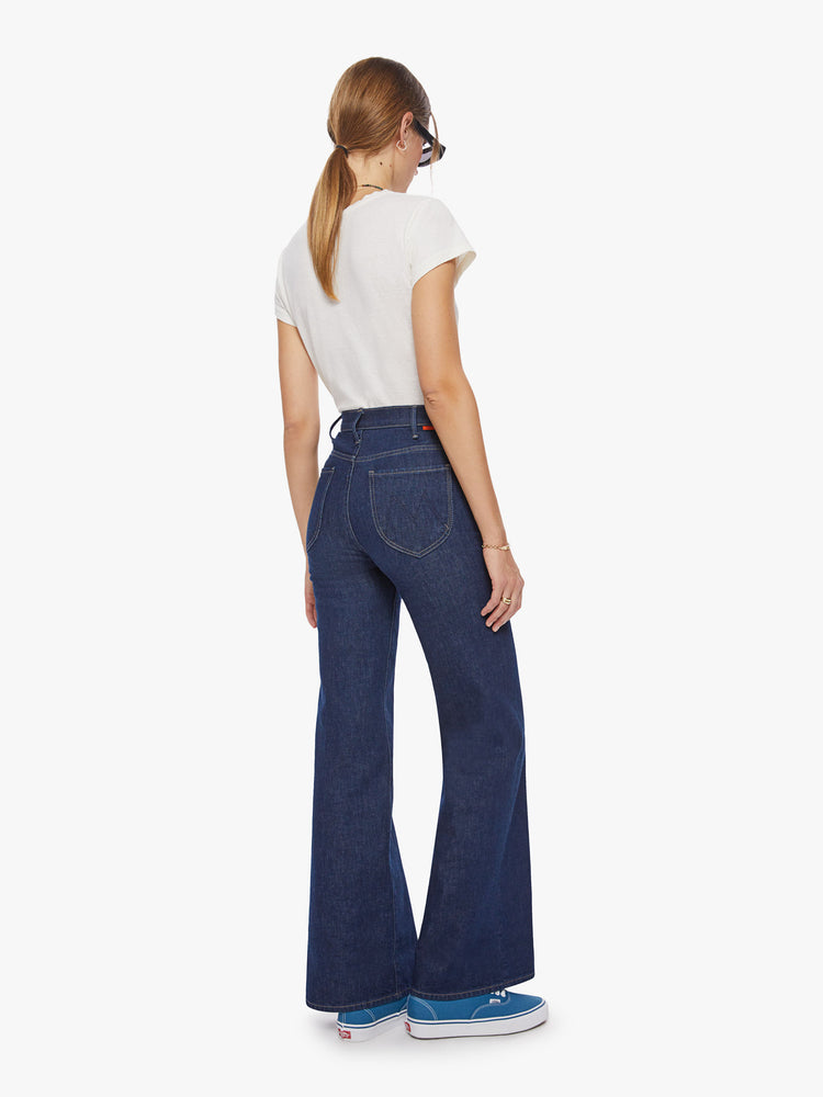 Back view of a woman high-rise jeans with a 34-inch inseam, clean hem and curved patch pockets on the back in a dark blue wash.