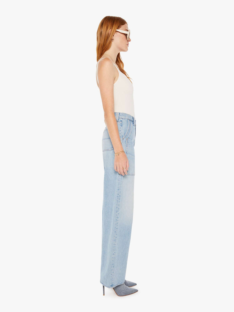 Side view of a womens light blue denim featuring a high rise, a wide straight leg, and front patch pockets.