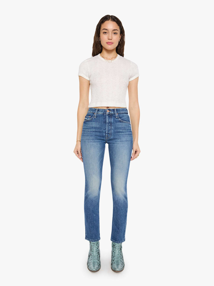 Front view of a woman in med blue high-waisted straight-leg jeans with a button fly, 29-inch inseam and a clean hem.