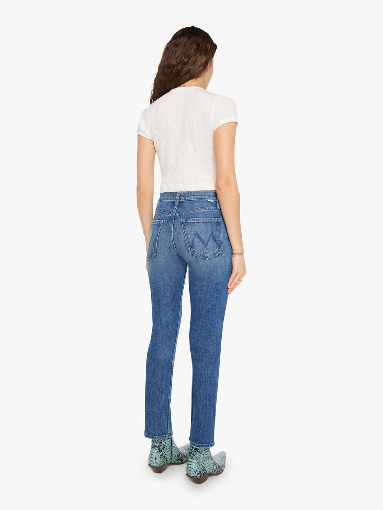 Back view of a woman in med blue high-waisted straight-leg jeans with a button fly, 29-inch inseam and a clean hem.