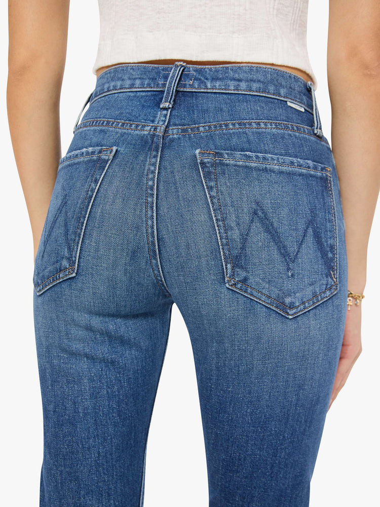 Close up back view of a woman in med blue high-waisted straight-leg jeans with a button fly, 29-inch inseam and a clean hem.