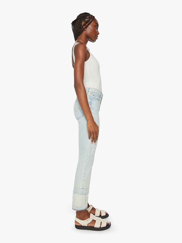 Side view of a woman light blue wash mid-rise bootcut has a 29-inch inseam and a frayed, double hem.