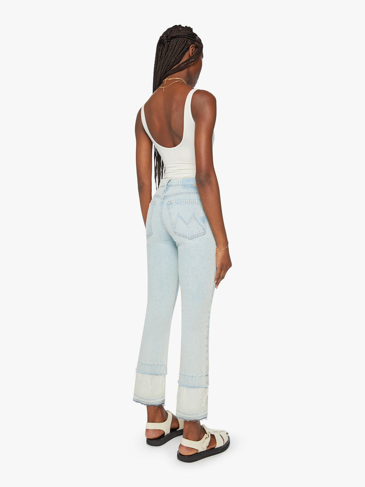 Back view of a woman light blue wash mid-rise bootcut has a 29-inch inseam and a frayed, double hem.