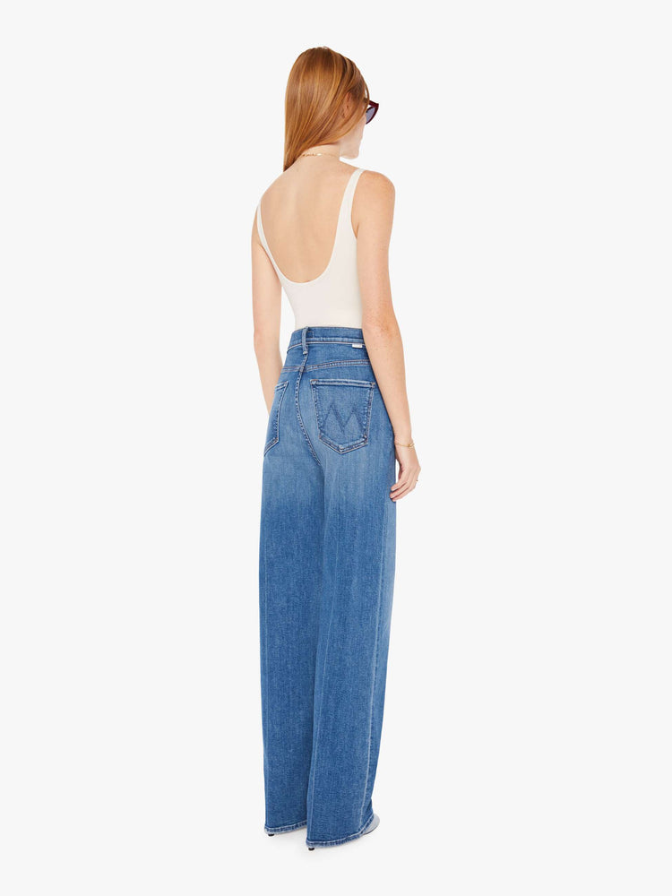 Back view of a womens medium blue wash jean featuring a super high rise and a wide full length leg.