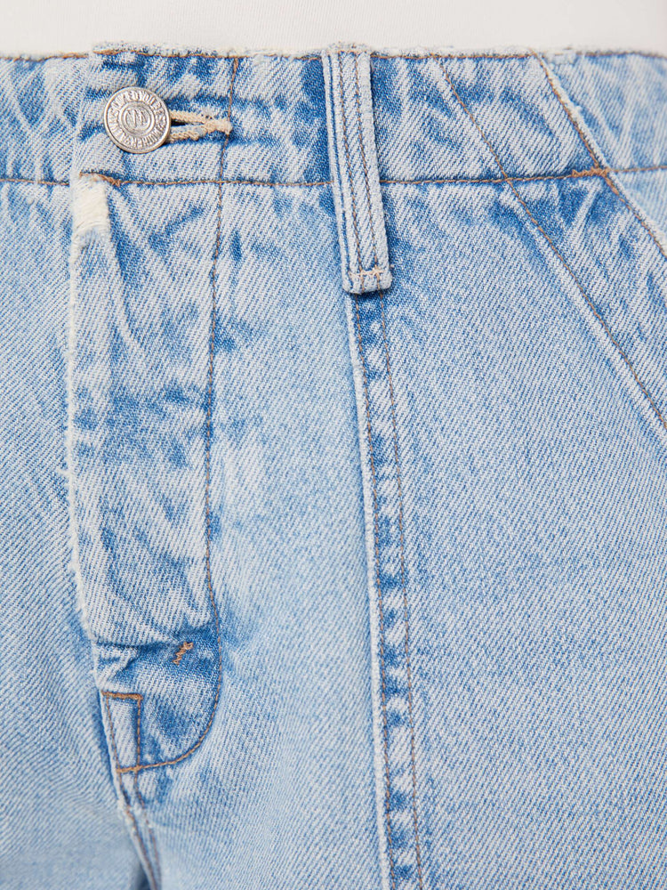 A close up swatch detail view of a light blue wash jean with darker blue hues near the seams, silver hardware, and contrast brown thread.