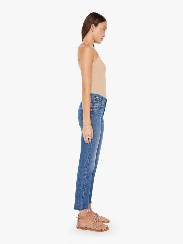 Side view of a womens medium blue jean featuring a mid rise, a straight leg, and an ankle length fray.