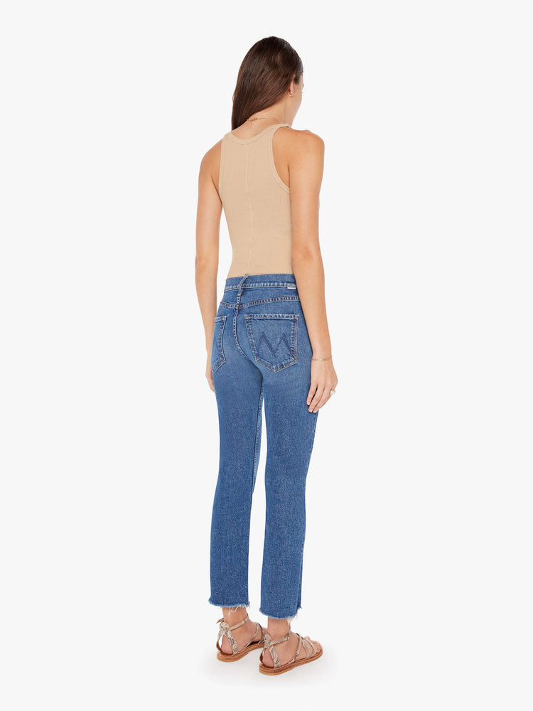 Back view of a womens medium blue jean featuring a mid rise, a straight leg, and an ankle length fray.
