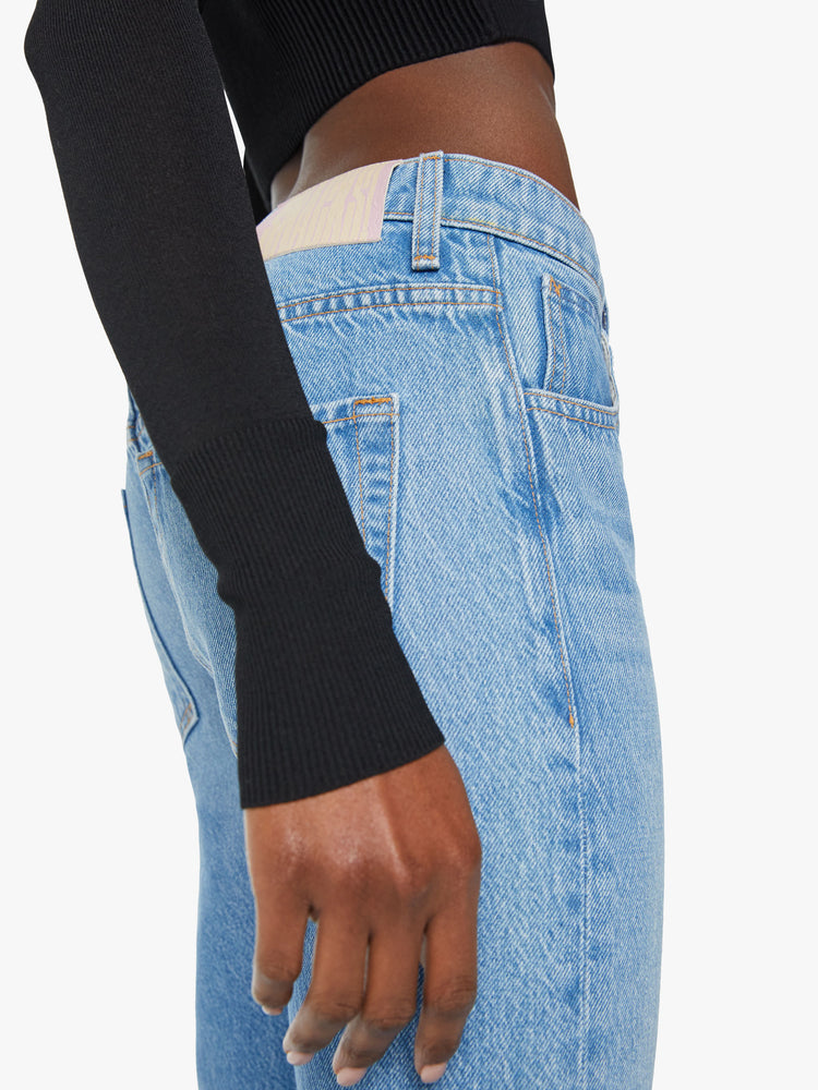 Close up side view of a woman low rise straight leg with a clean 31 inch inseam in a light blue wash.