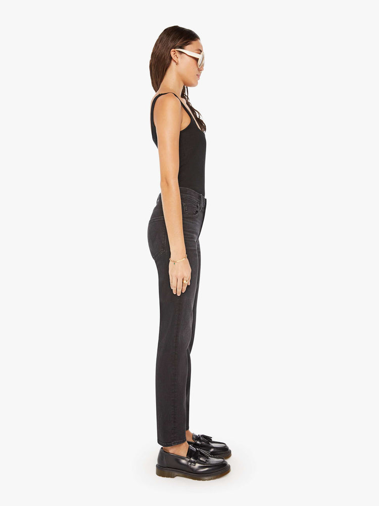Side view of a woman in a black high-waisted jeans with a narrow straight leg, zip fly and a 29-inch inseam with a clean hem.
