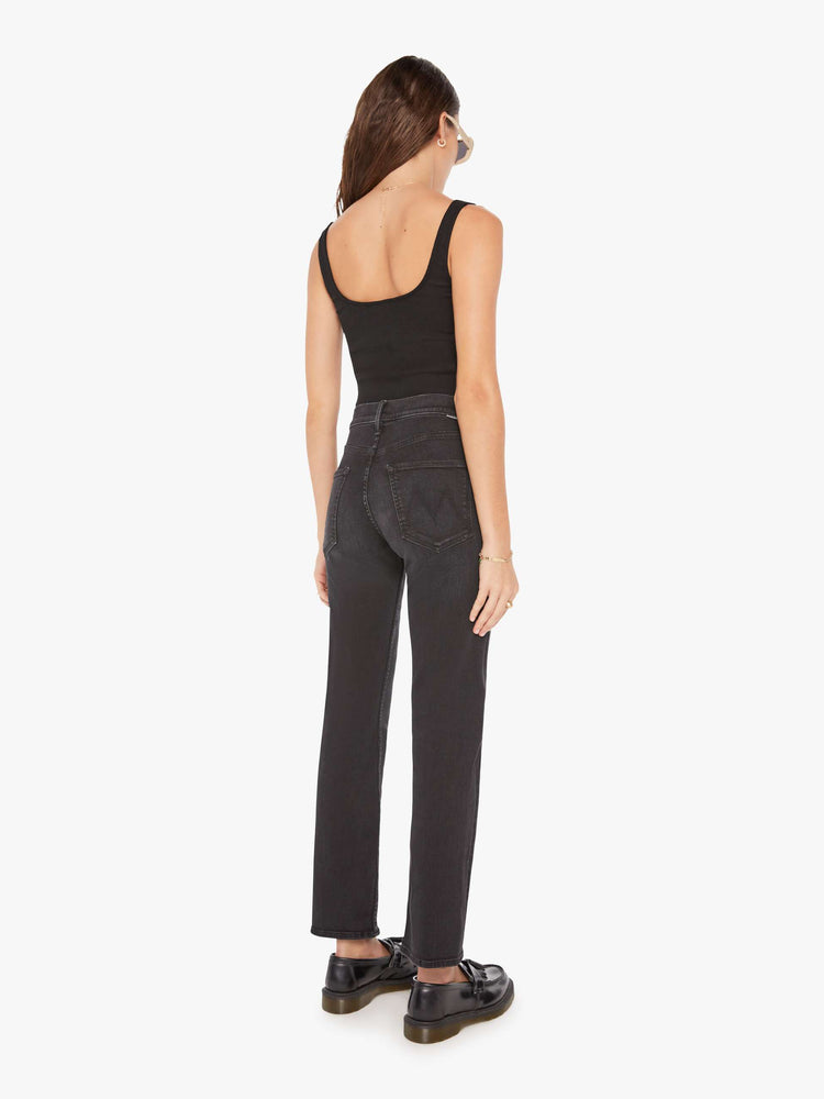 Back view of a woman in a black high-waisted jeans with a narrow straight leg, zip fly and a 29-inch inseam with a clean hem.