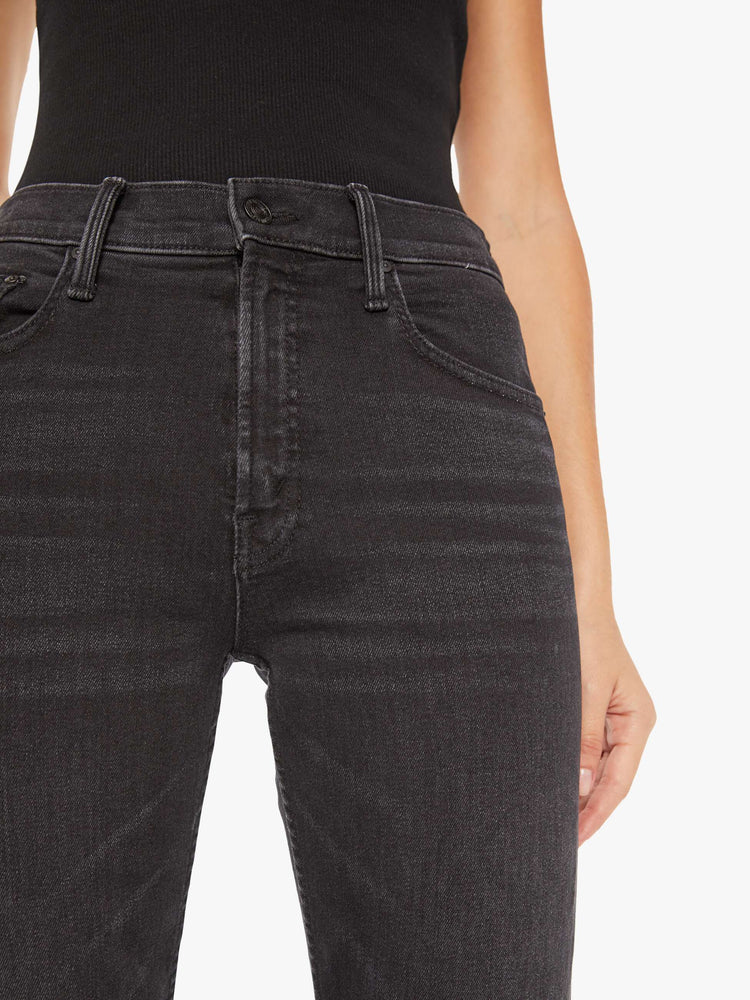 Close up view of a woman in a black high-waisted jeans with a narrow straight leg, zip fly and a 29-inch inseam with a clean hem.