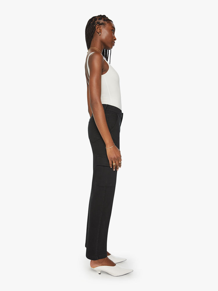 Side view of a woman high-waisted jeans with a wide straight leg, cargo pockets, zip fly and a long 32-inch inseam in a black wash.