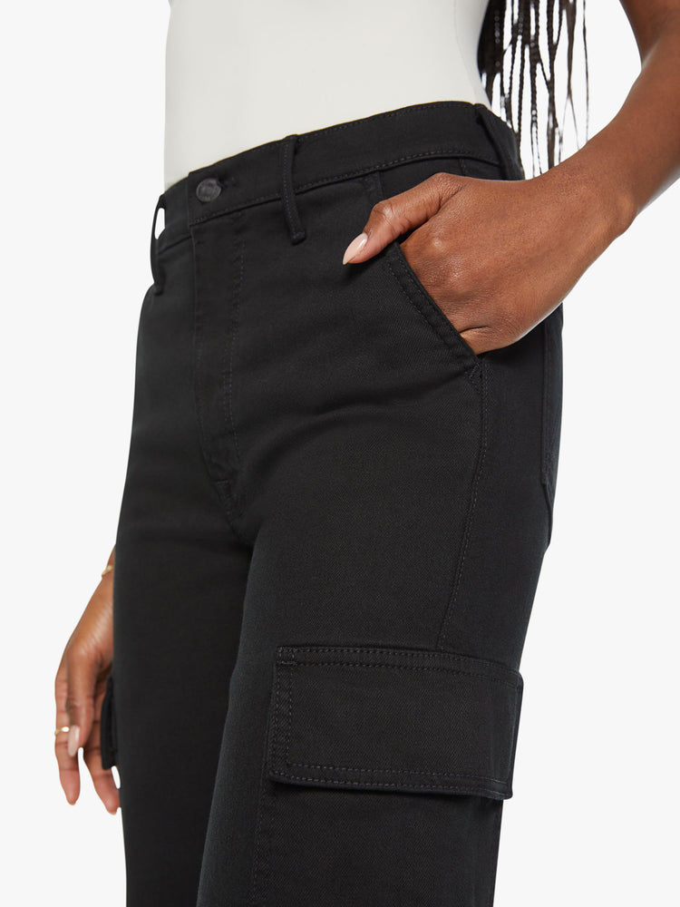 Waist view of a woman high-waisted jeans with a wide straight leg, cargo pockets, zip fly and a long 32-inch inseam in a black wash.