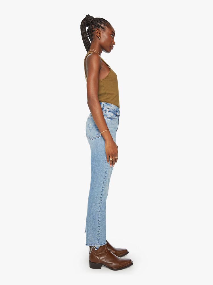 Side view of a woman slim straight-leg jean with a button fly, low-set back pockets, a high waist and a 29-inch inseam with a chewed hem in a light blue wash.
