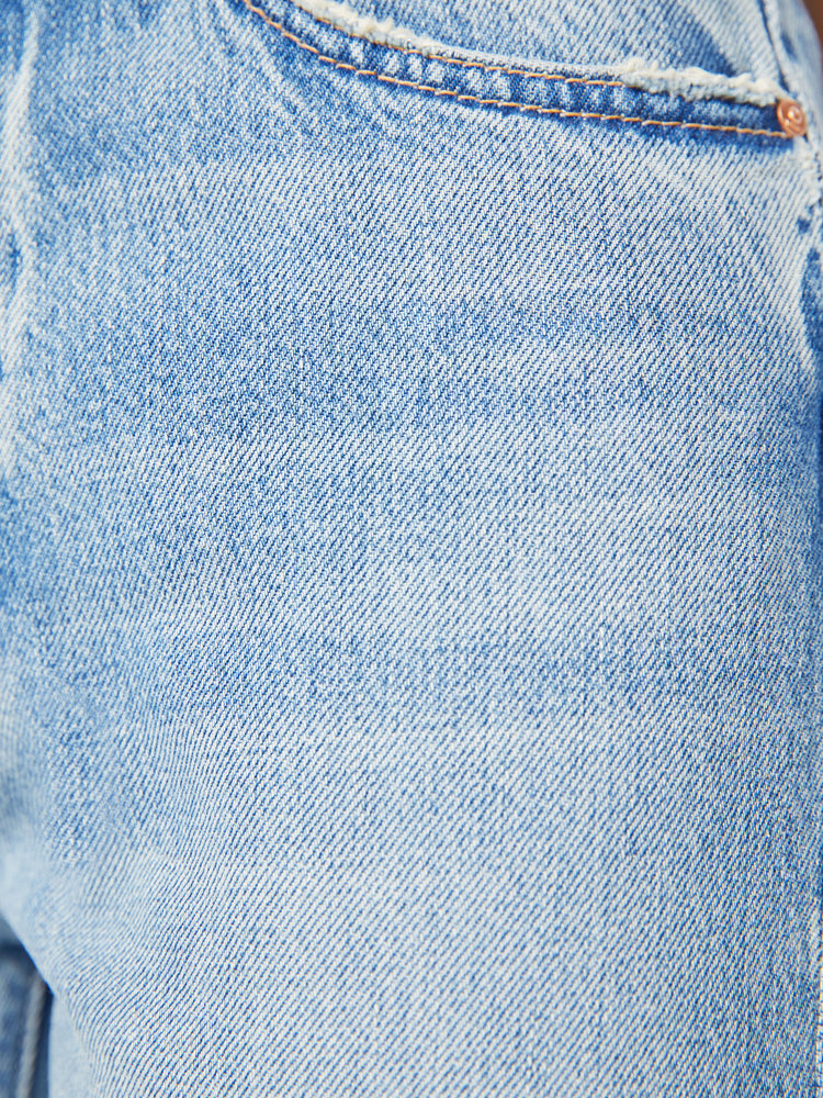 Swatch view of a woman slim straight-leg jean with a button fly, low-set back pockets, a high waist and a 29-inch inseam with a chewed hem in a light blue wash.