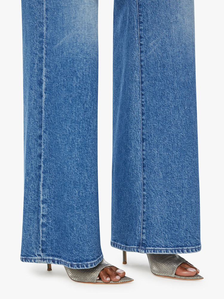 Hem view of a woman wide leg jean with a zip fly, low-set back pockets, high-rise with a slouchy fit and a 32-inch inseam in mid blue wash.