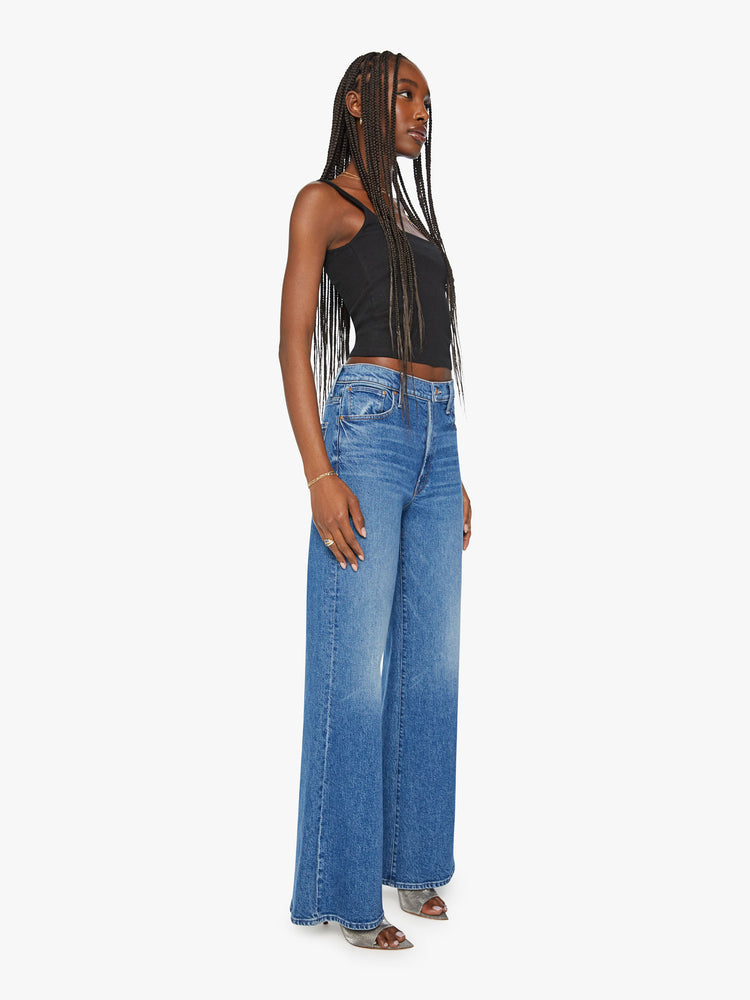 Side view of a woman wide leg jean with a zip fly, low-set back pockets, high-rise with a slouchy fit and a 32-inch inseam in mid blue wash.