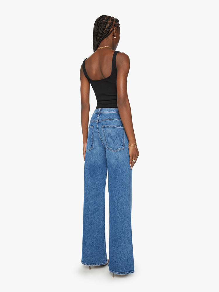 Back view of a woman wide leg jean with a zip fly, low-set back pockets, high-rise with a slouchy fit and a 32-inch inseam in mid blue wash.
