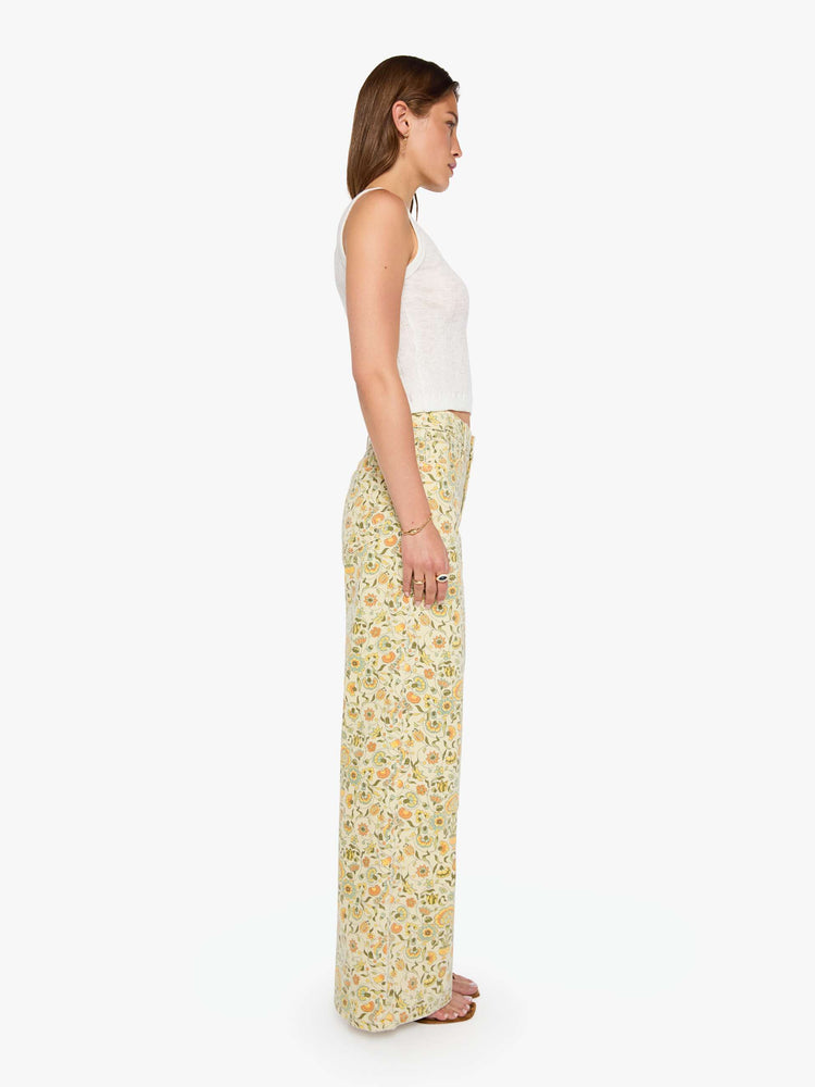 Side view of a woman in a pale yellow fresh florals  wide legs pant with a high rise with a slightly dropped crotch, zip fly, low-set back pockets and a 32-inch inseam with a clean hem.