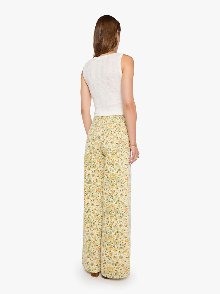 Back view of a woman in a pale yellow fresh florals  wide legs pant with a high rise with a slightly dropped crotch, zip fly, low-set back pockets and a 32-inch inseam with a clean hem.
