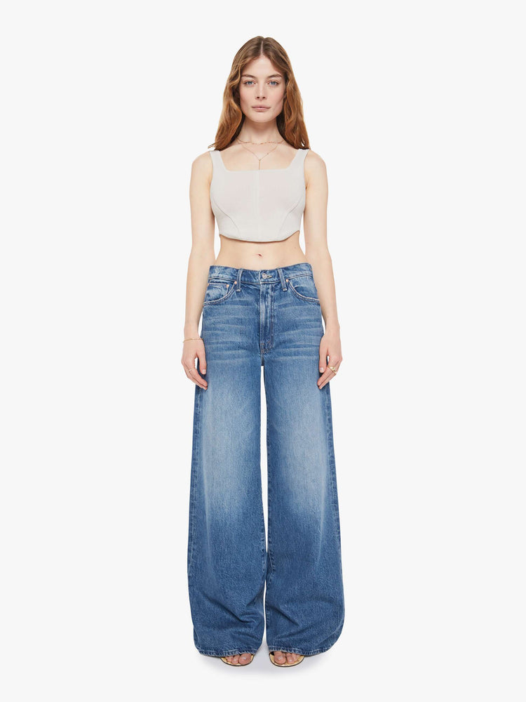 Front view of a woman in a med blue wide-leg jeans feature a slightly dropped crotch, zip fly, low-set back pockets and a 32-inch inseam.