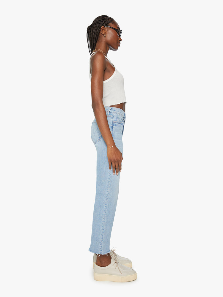 Side view of woman high-rise, straight-leg with an ankle-length inseam and a frayed hem in a light blue wash.