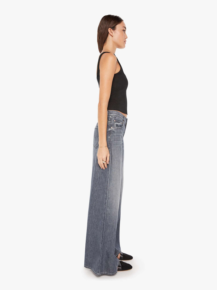 Side view of a womens grey wash jean featuring a high rise and a wide leg.