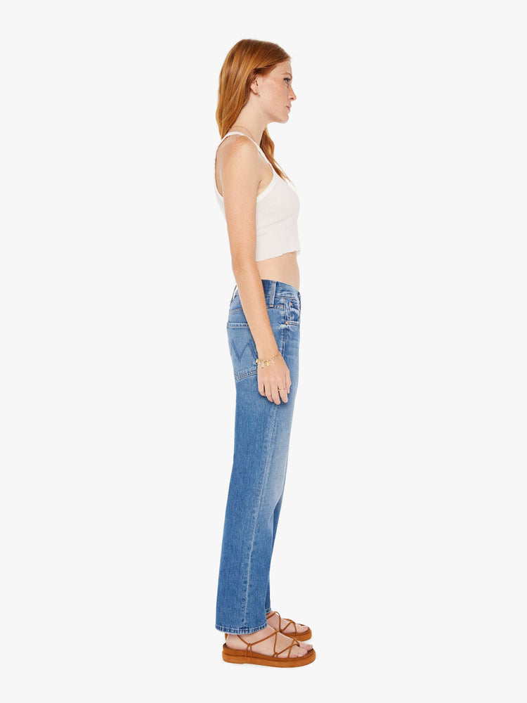 Side view of a womens medium blue wash jean featuring a mid rise with a slouchy fit and straight leg,